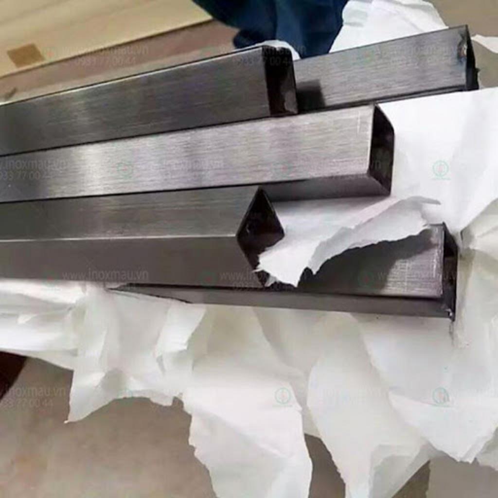 Nhân viên đang vệ sinh thiết bị làm bằng hộp inox trong nhà máy.